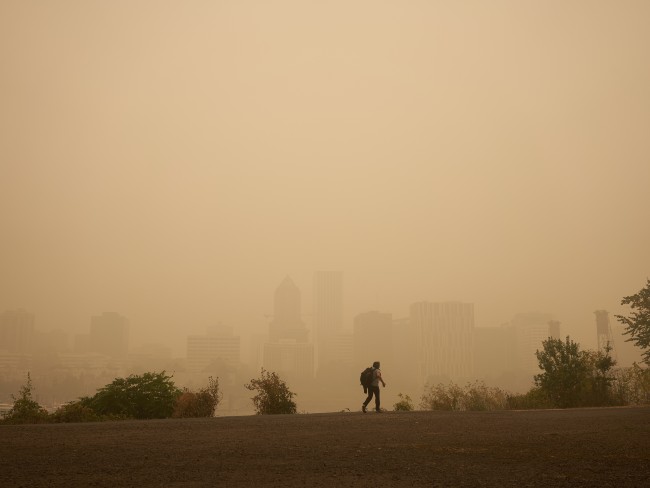 man walking through heavy smoke from wildfires