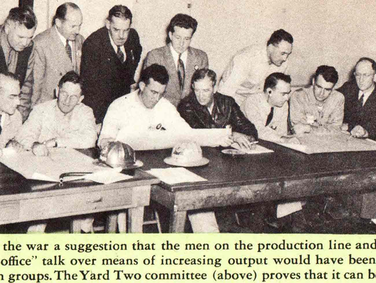 Photo of a group of men seated and standing at a long table