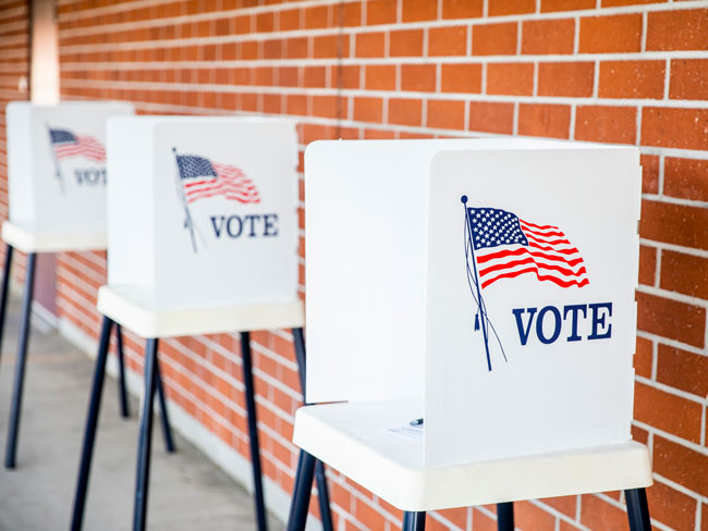 3 private voting booths against a brick wall