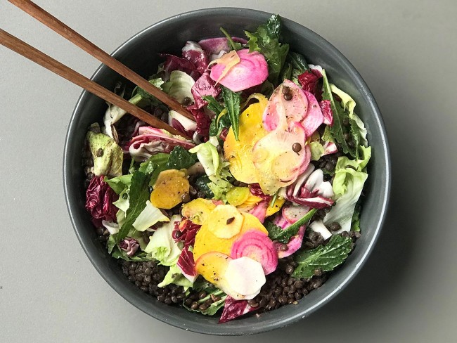 Bowl of salad with lettuce, kale, sliced beets, radishes, and lentils