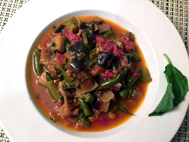 A hearty bowl of Armenian batilgian stew filled with healthy fresh vegetables in a white bowl.