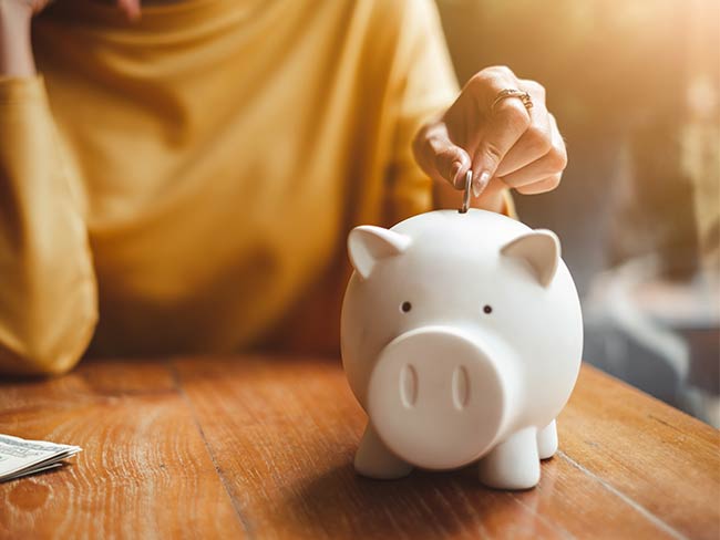 Person putting a coin into a piggy bank