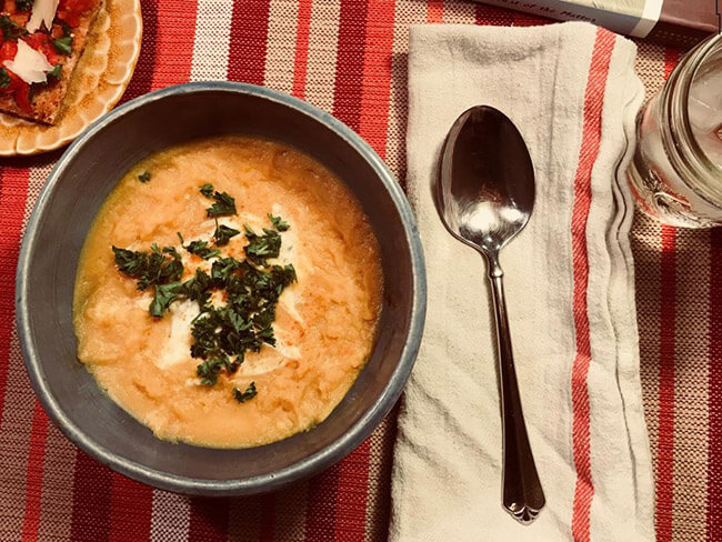 bowl of butternut squash and lentil soup with garnish of chopped parsley