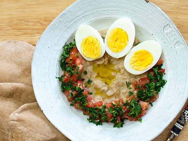 Pureed canellini bean stew served with halved hard-boiled and garnished with diced tomato and parsley.