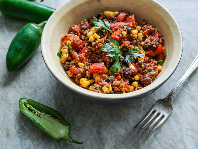 Mexican quinoa salad with black beans, corn, and tomatoes with jalapenos on the side