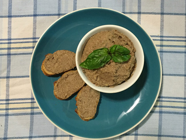 Mushroom pâté on toast with basil served on a blue plate.