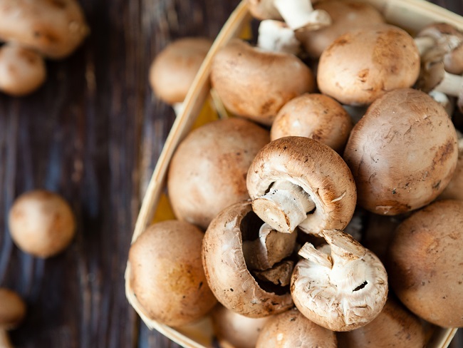 Champignons in a basket on dark boards, food.