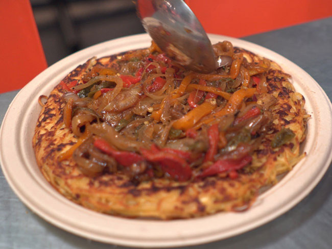 Pasta frittata in a skillet, topped with summer vegetables.