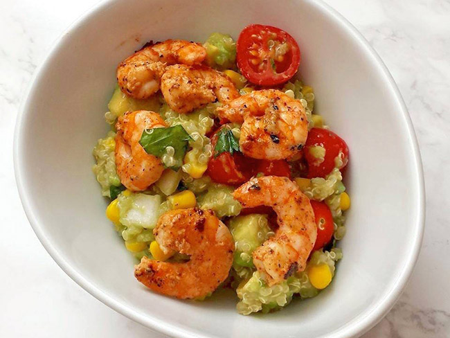 Quinoa and avocado salad with chili-lime shrimp in a white bowl.