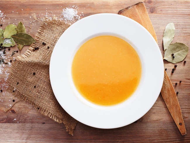 Saffron soup on wood board with herbs