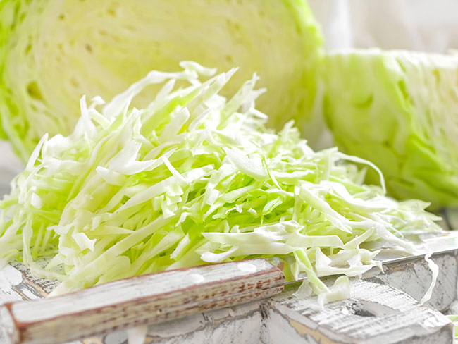 Cutting board with shredded green cabbage