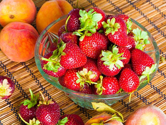 Fresh nectarines, peaches, and strawberries on a tabletop. 