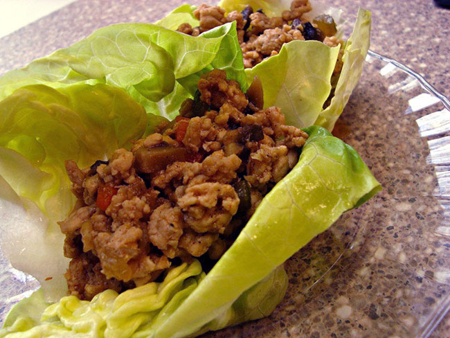 Lettuce wraps with turkey on a glass plate.